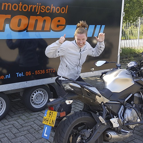 Geslaagde leerling juicht naast de lesmotor van Rijschool Motodrome