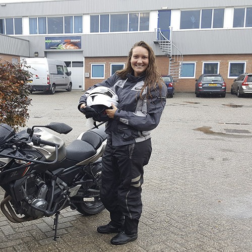 Geslaagde leerling met haar helm naast de lesmotor